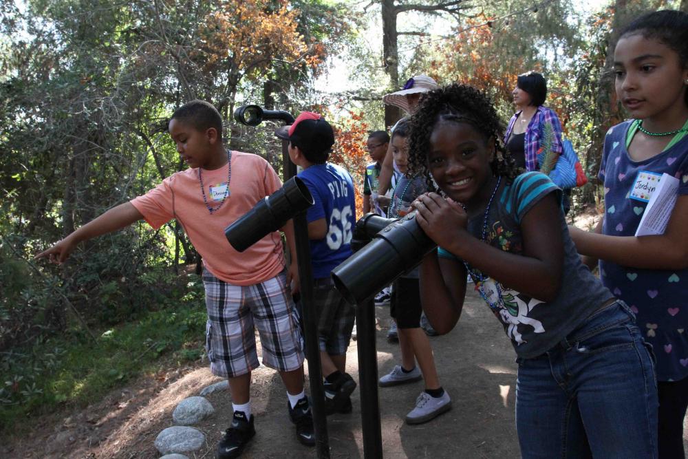Girl looks through mounted telescope in a group of kids at an "Every Kid in a Park" event in Los Angeles County, California, in 2015