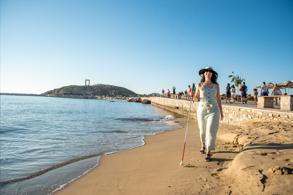 person walking on a beach with a walking stick