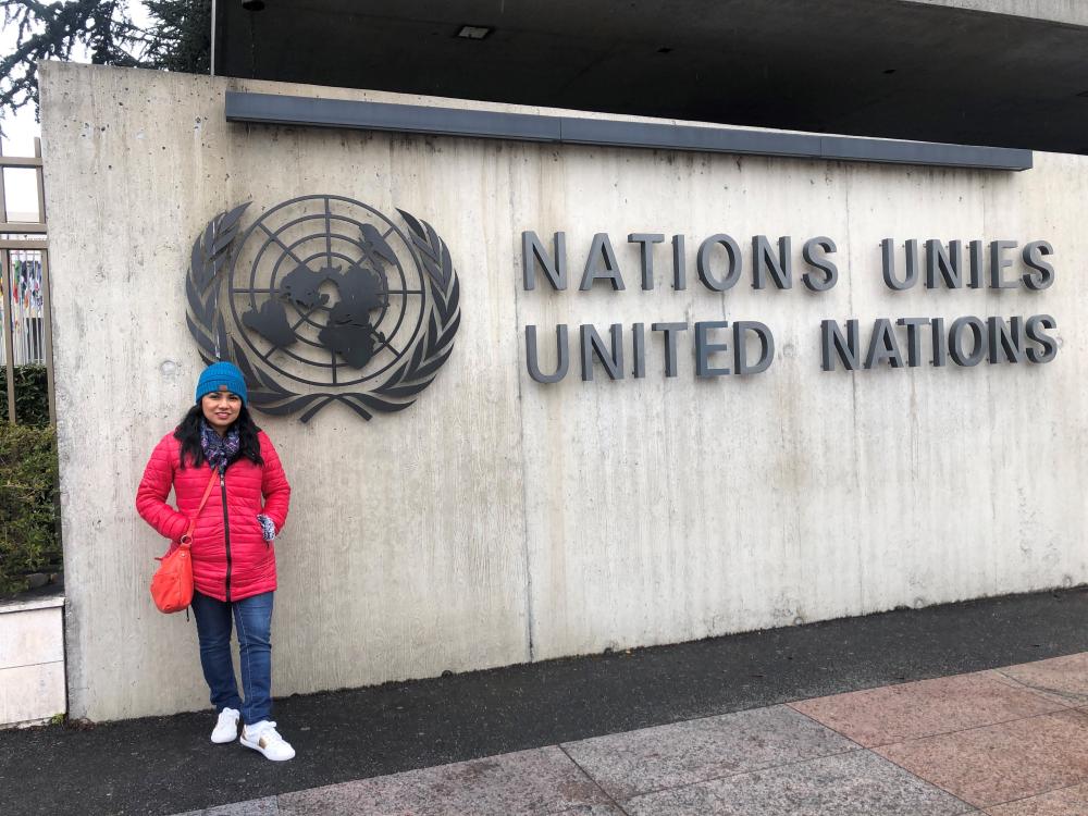 person posing in front of a sign that says "nation unies, united nations"