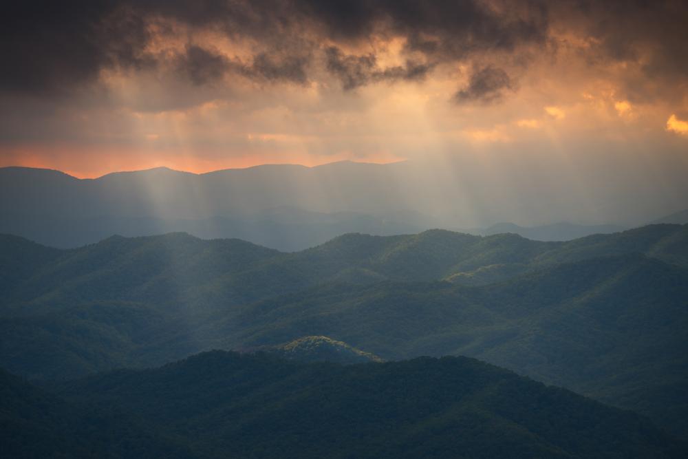 Sun peeking through clouds over mountain range, North Carolina