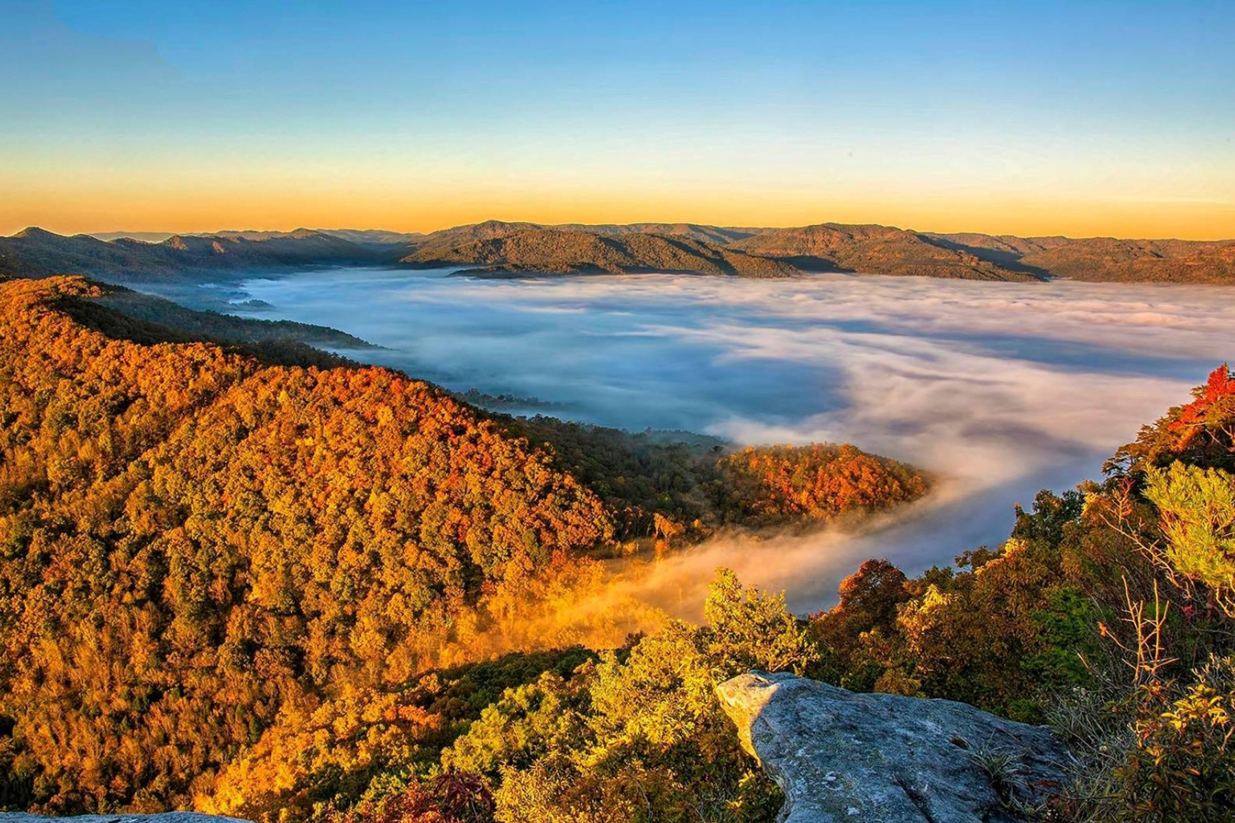 View of clouds on mountain peaks with autumn leaves