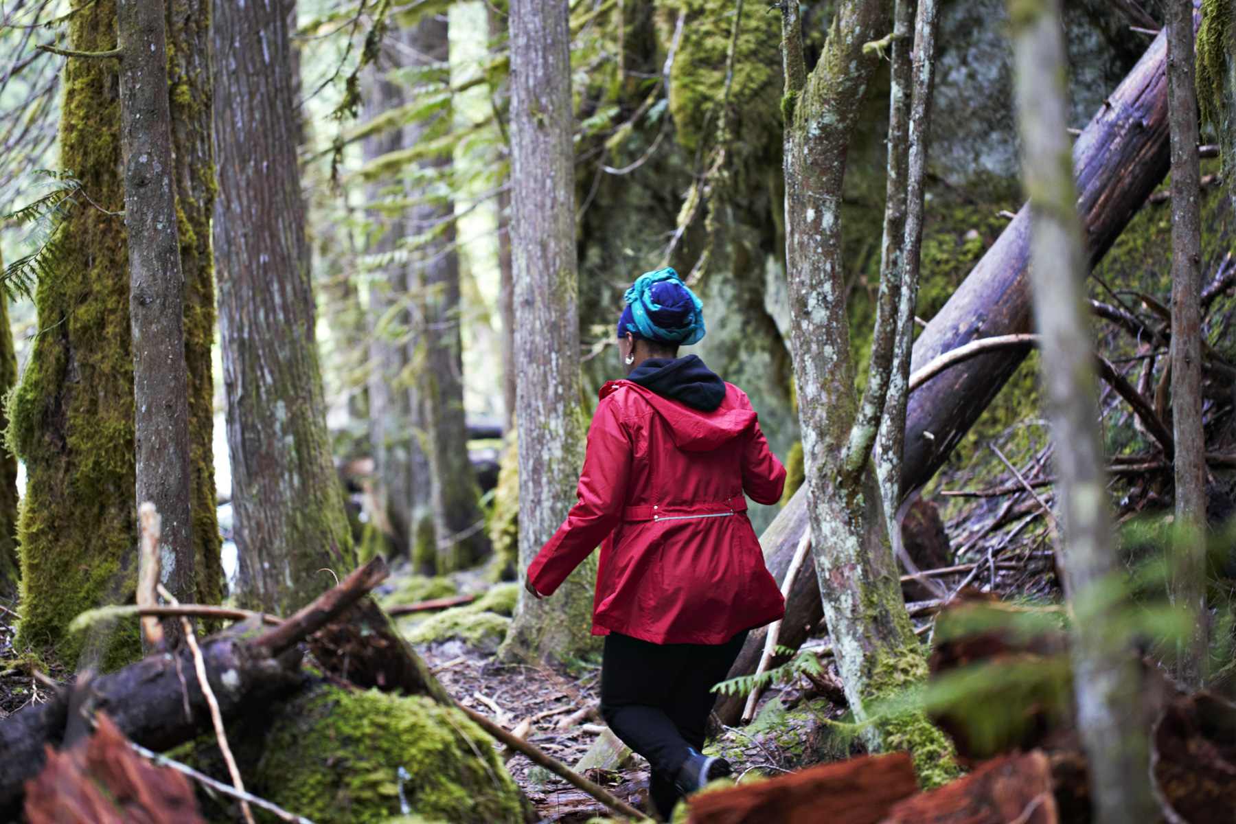 A woman walking on a trail in the forest.