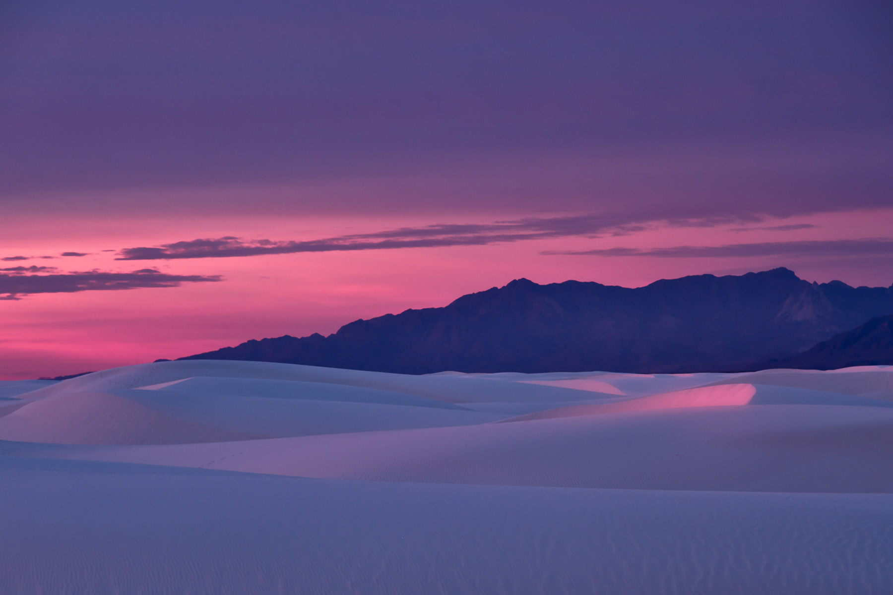 sunset colors over towers of white sands and mountains in the background