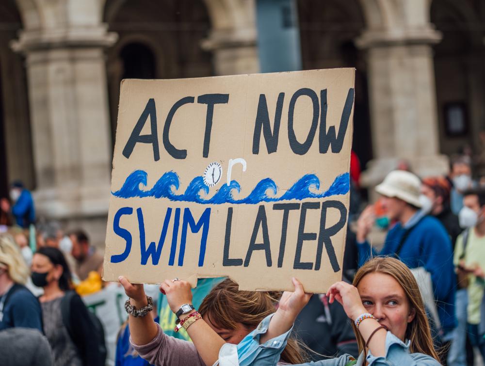 Protesters at Global Climate Strike holding a banner with the message "Act now or swim later"