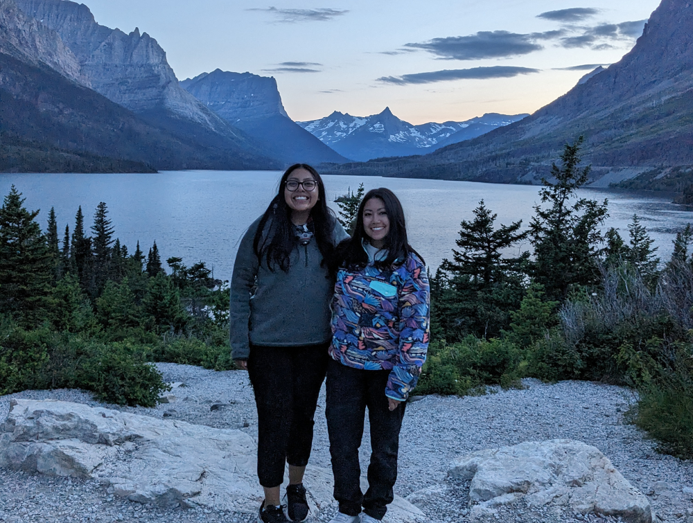 two people pose with lake and mountains in the background