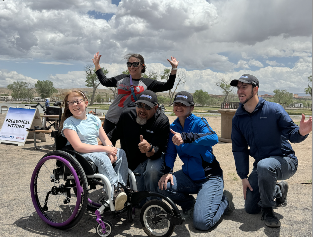 three adults and a child on a wheelchair posing for picture 