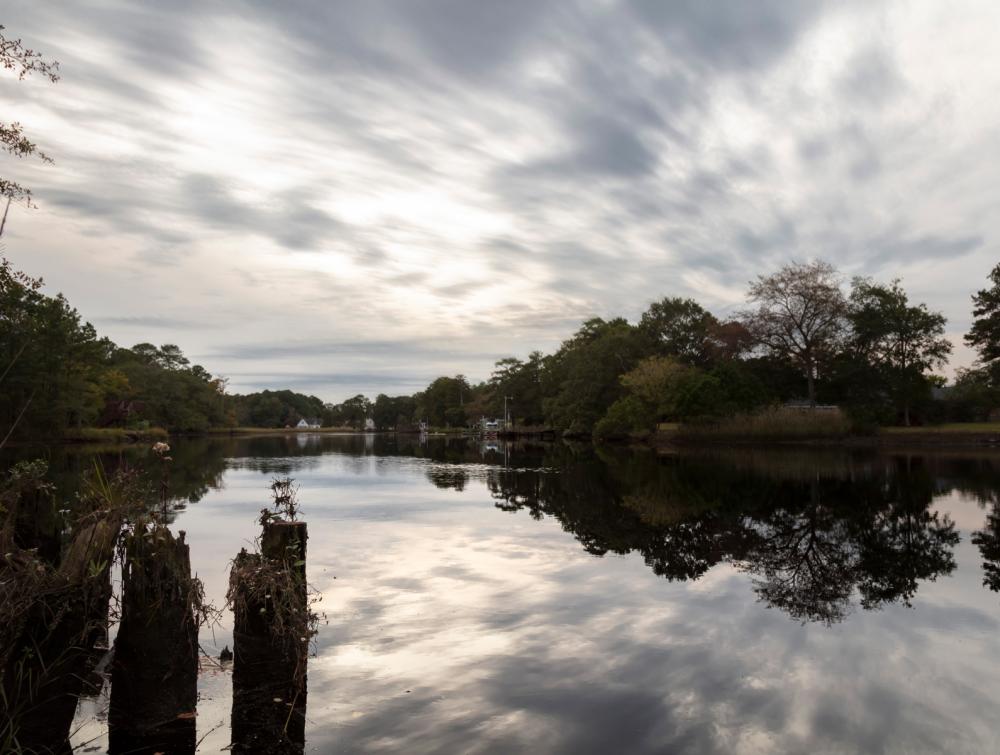 Dark clouds reflected in water's surface fringed by trees