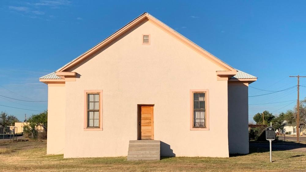 white structure that looks like a house, with one door and a window on each side