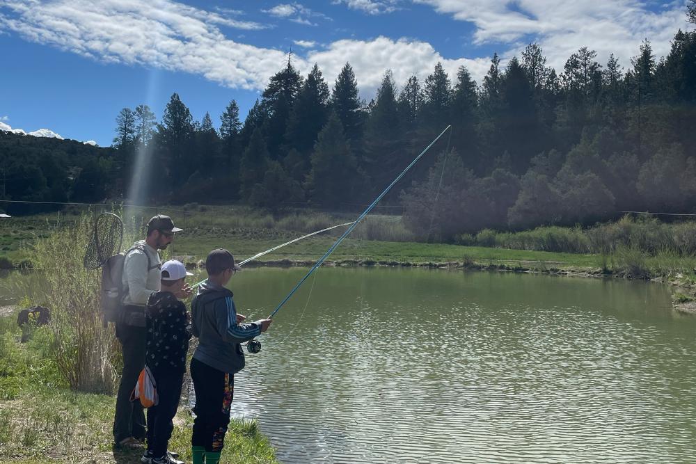 students fly fishing at river surrounded by trees