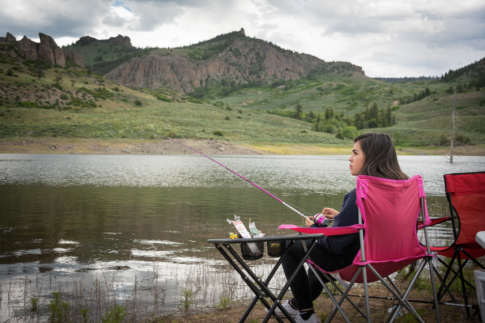 person sitting while fishing, with mountain in the background