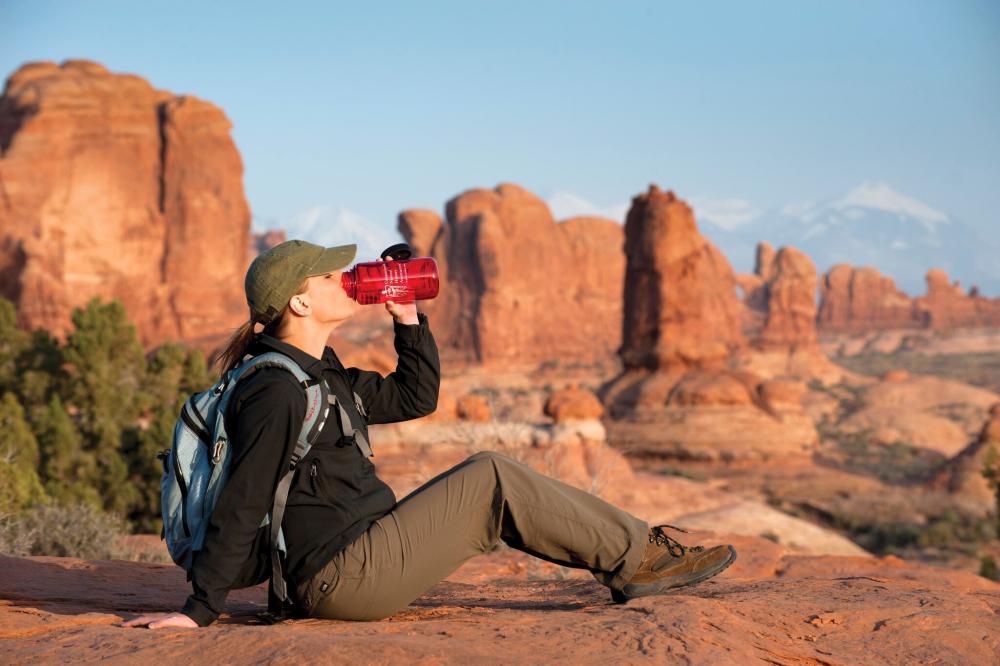 woman drinking water surrounded by rocks