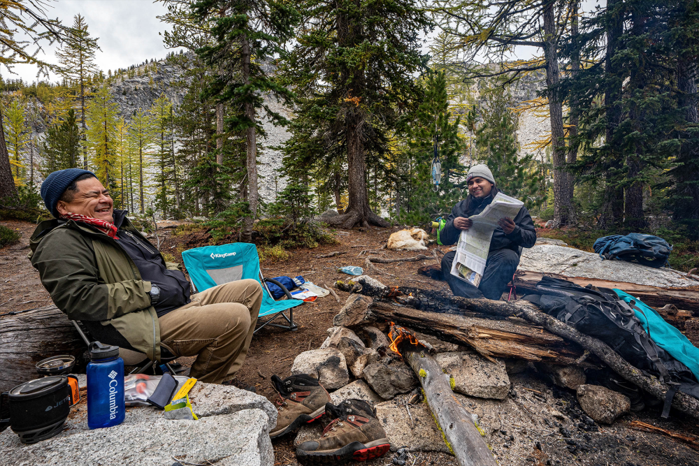 people sitting on camping shares surrounded by forest trees