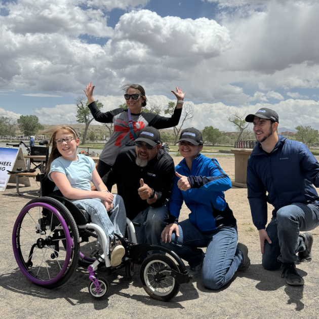 three adults and a child on a wheelchair posing for picture 