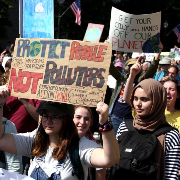Women in foreground marching at rally and holding signs during Global Climate Strike in 2019 in Washington, DC 